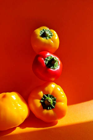 four yellow and red pepper on an orange background. harvest time. Levitating peppers