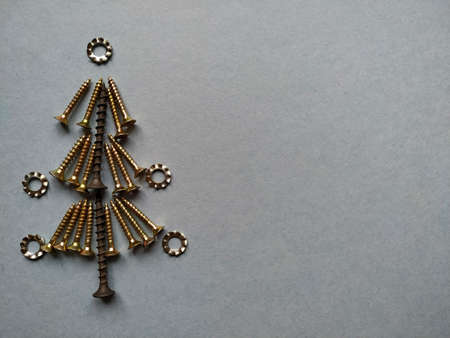 Christmas tree built of construction screws on a blue background.