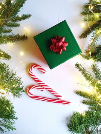 christmas gichristmas gift with candy canes surrounded by fir branches with glowing garlands