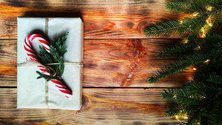 christmas gichristmas gift with candy canes surrounded by fir branches with glowing garlandsft with candy canes surrounded by fir branches with glowing garlandsの写真素材