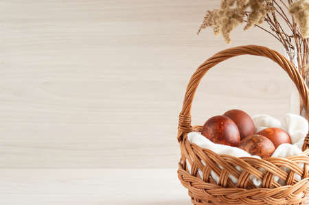 Easter eggs painted with natural dyes in a wicker basket. concept of farm products