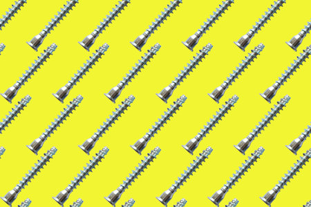 seamless pattern of silver screws on yellow background.