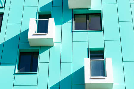 front view of a multi-storey green modern building with tiny balconies.の写真素材