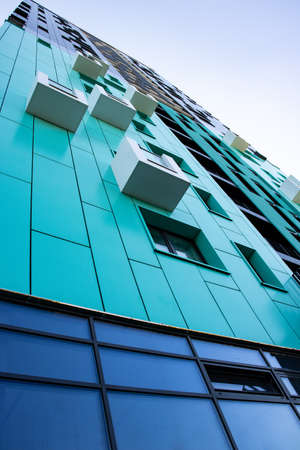bottom view of a modern aqua colored skyscraper with white little balconies. urban jungleの写真素材