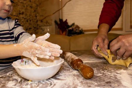 little boy preparing christmas cookies together with his grandmother. Close-upの写真素材