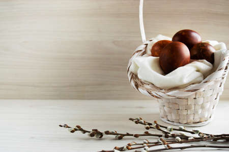 Easter eggs painted with natural dyes on a white fabric, decorated with willow branchesの写真素材