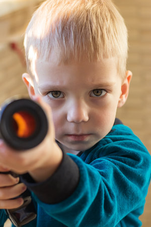 Toddler looking at the camera with a serious angry face and aiming with a childs pump gunの写真素材