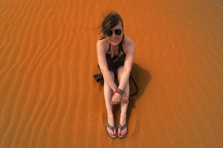 Caucasian woman sitting in sand on top of a sand dune の写真素材