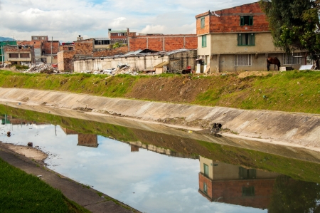 A lower class neighborhood reflected in a river in Bogota, Colombiaの写真素材