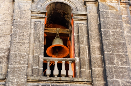 Orange light falling on a bell in the bell tower of the cathedral of Mexico Cityの写真素材