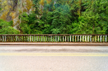 Concrete railing of historic Highway 30 with a beautiful green rainforest passing through the Columbia River Gorge in Oregon の写真素材