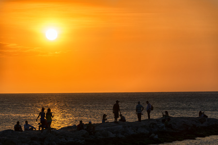 Silhouettes of people enjoying a beach a sunset in Santa Marta, Colombiaの写真素材