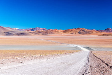 A barren yet colorful landscape with a road leading into the distance near Uyuni, Boliviaの写真素材