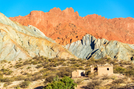 A ruined building at the base of dramatic colorful hills in the small town of Quiriza near Tupiza,...
