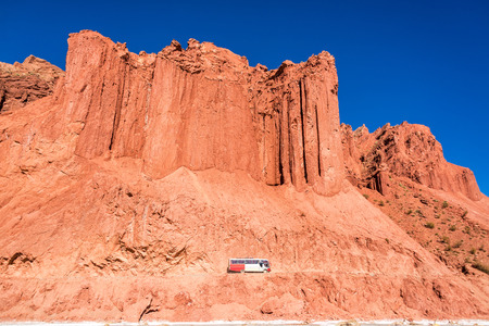 Bus passing by dramatic red cliffs near Tupiza, Boliviaの写真素材