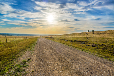 Blue and yellow sunrise over a dirt road near Buffalo, Wyomingの写真素材