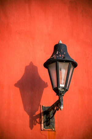 Old style street light on a red wall in the historic colonial center of Cartagena, Colombiaの写真素材