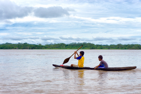 IQUITOS, PERU - MARCH 13: Two children navigate the Amazon River in a dugout canoe near Iquitos, Peru on March 13, 2015のeditorial素材