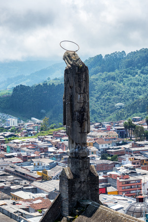 Statue on a cathedral with the city of Manizales, Colombia visible in the backgroundの写真素材