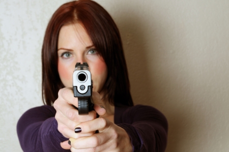 Image of female pointing a gun at somebody breaking and enteringの写真素材