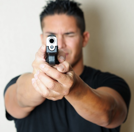 Image of young male pointing gun.  Focus on barrel of gun.の写真素材