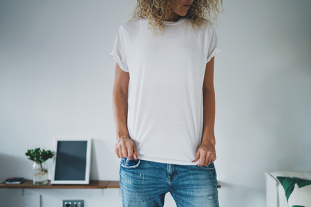 Cropped photo of a pretty girl dressed in casual clothes demonstrating an empty place for design on a white blank T-shirt.の写真素材