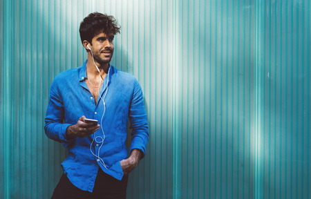 young attractive model look male listening to music on mobile phone using headphones.の写真素材