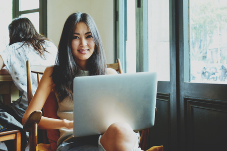 Casual asian young woman using laptop for distance education at coffee shop.portrait of an attractive girl shopping online on a modern computer. young girl communicates with friends via web cameraの写真素材