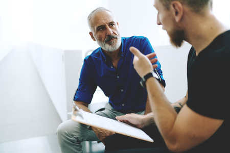 Professional journalists discussing new assignment from the publisher to cover all the points of the upcoming international summit. CEO and manager talking on a new company sales report in the office.の写真素材