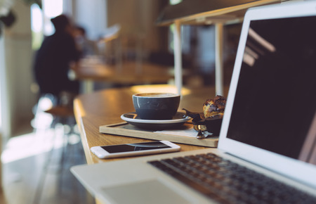 Cropped photo of the open laptop in a modern coworking space. Black blank screen for your logo, design, text or content. Laptop computer with blank screen on a vintage wooden table.の写真素材