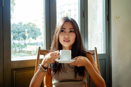 Young beautiful asian businesswoman drinking coffee / tea in a coffee shopの写真素材