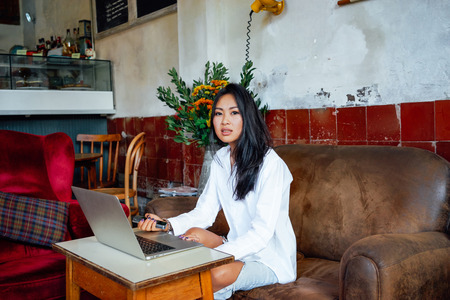 portret of young asian female freelancer using laptop computer for distance job at coffee shopの写真素材