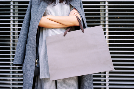 Close up female hands holding a blank paper bag with empty space for your text or logoの写真素材