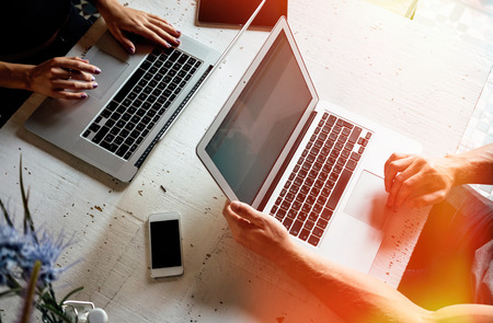 top view of a male's hands and female's hands typing on the keyboard opposite of each other. various...