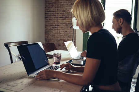 Young female and young man freelancers work with laptops in a loft interior.の写真素材