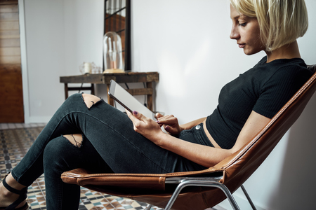 young woman writes in a blog on her digital tablet in a vintage interiorの写真素材