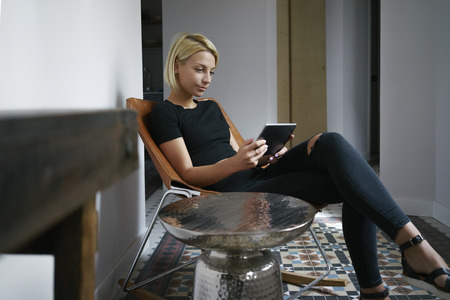 young female writes in a blog on her digital tablet in a vintage interiorの写真素材