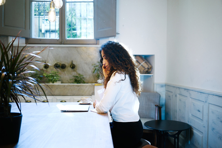 Young elegant business woman talking on the smart-phone in a cafe.attractive freelancer working with a laptop in a coffee-shopの写真素材