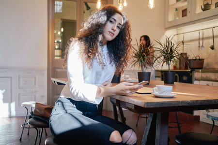 young attractive student wrote a message on her smartphone. beautiful business woman preparing for a business meeting in a cafe during the lunch breakの写真素材
