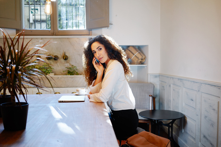 Young attractive business woman making a business call during the lunch break. beautiful woman working with a laptop in a cafeの写真素材