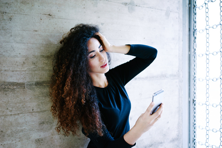 young attractive business woman take a self portrait with her smart phone.Gorgeous young woman photographing herself using her mobile phone.Caucasian female taking selfie with her smart phone outside.の写真素材