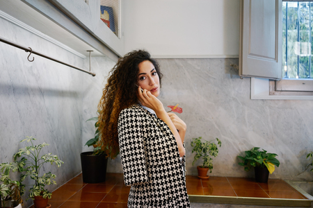 Young attractive businesswoman with long curly hair talking on cell telephone.brunette Caucasian girl talking on smart-phone in coffee-shopの写真素材