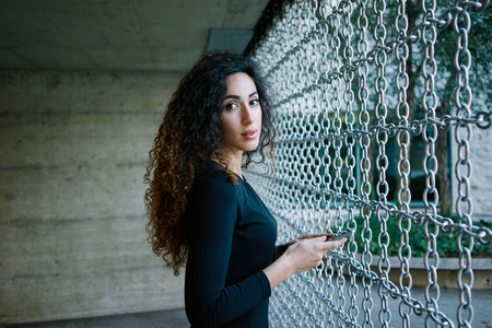 young attractive woman writing a message on her smartphone against a background of contemporary...