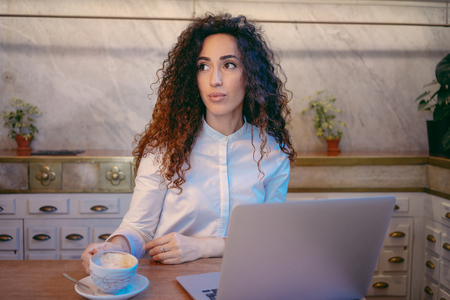 Young attractive business-woman working with her laptop in a coffee-shop and drink coffee.beautiful female freelancer working  in co-working spaceの写真素材