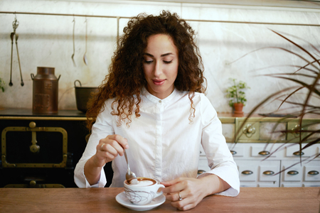 young beautiful female student drinking coffee in a cafe.attractive girl with long curly hair...