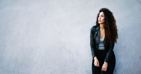 Charming young woman standing against street wall background with copy space area for your text message or informationの写真素材