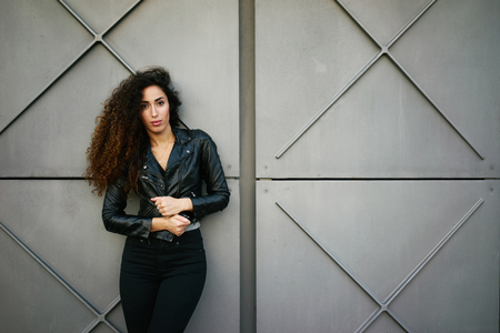 young appealing girl with a good figure and long curly hair against a background of gray concrete wall with copy space area for your text or designの写真素材