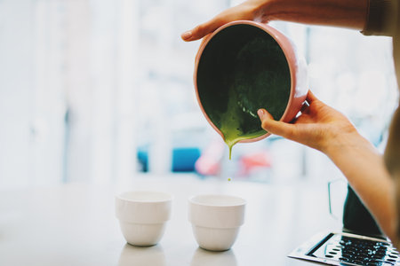 Closeup photo of gentle hands of a professional teamaker holding a bowl with freshly made...