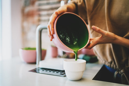 Super natural matcha tea made by professional barista in a coffee shop. Woman's hands holding a bowl with a matcha tea ready to be poured to the cup and served. Tea ceremony in a oriental style.の写真素材