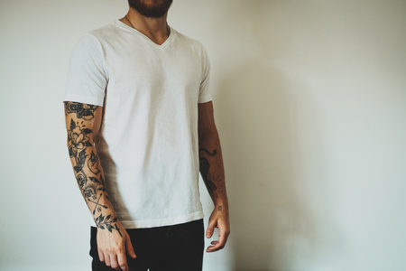 Cropped photo of a tattooed man dressed in casual clothes demonstrating an empty place for design on a white blank t-shirt. Horizontal mockup.の写真素材